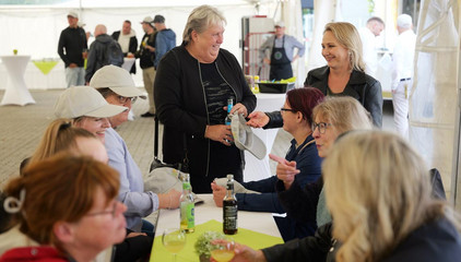 Mitarbeitende sitzen und stehen um einen Tisch im Festzelt und unterhalten sich fröhlich bei der Jubiläumsfeier 20 Jahre Albertinen Services Hamburg ASH in Rellingen.