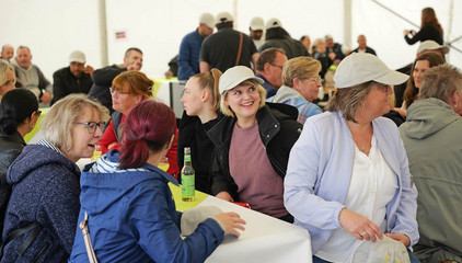 Mehrere Mitarbeitende sitzen zusammen an einem Tisch im Festzelt bei der Jubiläumsfeier 20 Jahre Albertinen Services Hamburg ASH in Rellingen.