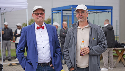 Zwei Mitarbeitende stehen vor dem Festzelt und blicken in die Kamera bei der Jubiläumsfeier 20 Jahre Albertinen Services Hamburg ASH in Rellingen.