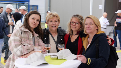 Vier Mitarbeiterinnen stehen um einen Tisch und blicken lächelnd in die Kamera bei der Jubiläumsfeier 20 Jahre Albertinen Services Hamburg ASH in Rellingen.