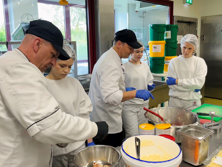 Mitarbeiter der Zentralküche zeigen Schülerinnen beim Girls’ Day praktische Arbeitsschritte bei der Zubereitung von Speisen. Mitarbeiter der Zentralküche zeigen Schülerinnen beim Girls’ Day praktische Arbeitsschritte bei der Zubereitung von Speisen.
