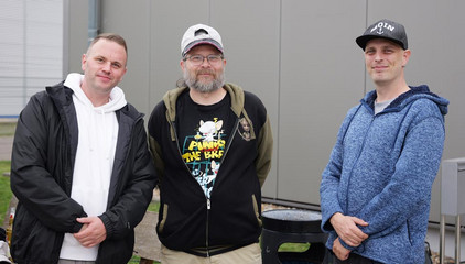 Drei Mitarbeiter stehen nebeneinander und blicken in die Kamera bei der Jubiläumsfeier 20 Jahre Albertinen Services Hamburg ASH in Rellingen.