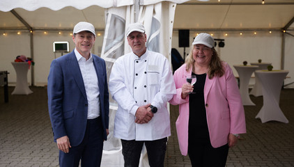 Die beiden Konzergeschäftsführenden Andrea Wichmann (rechts) und Dr. Thorsten Minuth (links) unterhalten sich mit Klaus-Dieter Böttcher, Leiter der Zentralküche Rellingen, und blicken lächelnd in die Kamera bei der Jubiläumsfeier 20 Jahre Albertinen Services Hamburg ASH in Rellingen.
