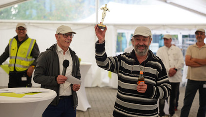 Ein Mitarbeiter hält eine menschliche Figur aus Metall in die Höhe bei der Jubiläumsfeier 20 Jahre Albertinen Services Hamburg ASH in Rellingen.